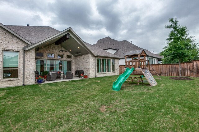 rear view of house with brick siding, a fenced backyard, an outdoor living space, a playground, and a lawn