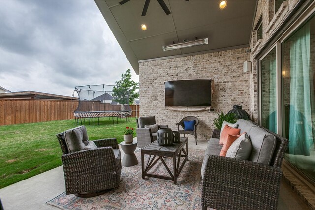 view of patio featuring a ceiling fan, a fenced backyard, a trampoline, and an outdoor hangout area