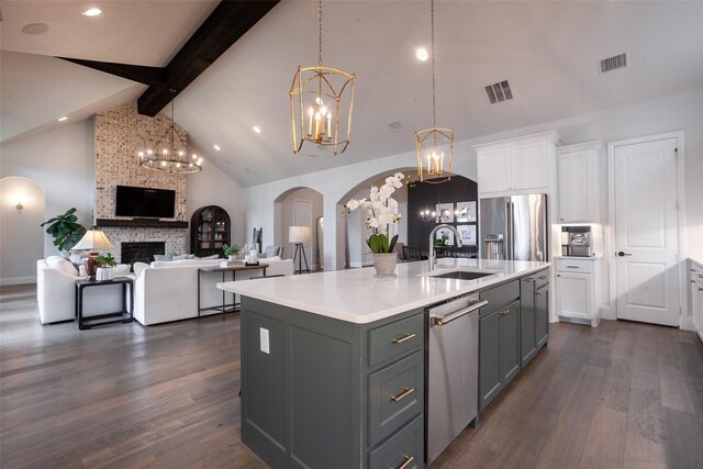 kitchen featuring arched walkways, beam ceiling, a sink, a chandelier, and stainless steel appliances