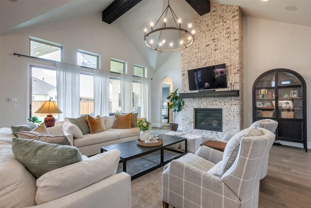 living room with an inviting chandelier, beam ceiling, wood finished floors, high vaulted ceiling, and arched walkways