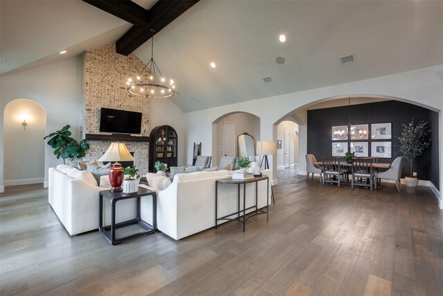 living area with beam ceiling, a chandelier, baseboards, wood finished floors, and visible vents