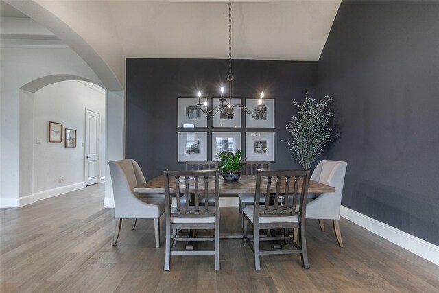 dining area with an inviting chandelier, arched walkways, baseboards, and wood finished floors