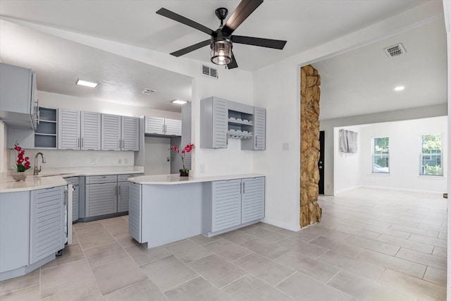 kitchen featuring open shelves, visible vents, a ceiling fan, gray cabinets, and a sink
