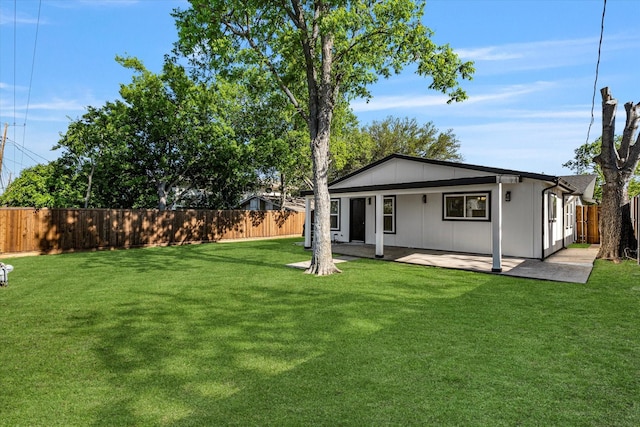 rear view of property featuring a lawn, a fenced backyard, and a patio area