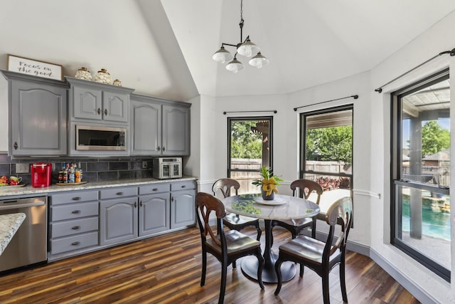 dining area with an inviting chandelier, dark wood-style flooring, and high vaulted ceiling