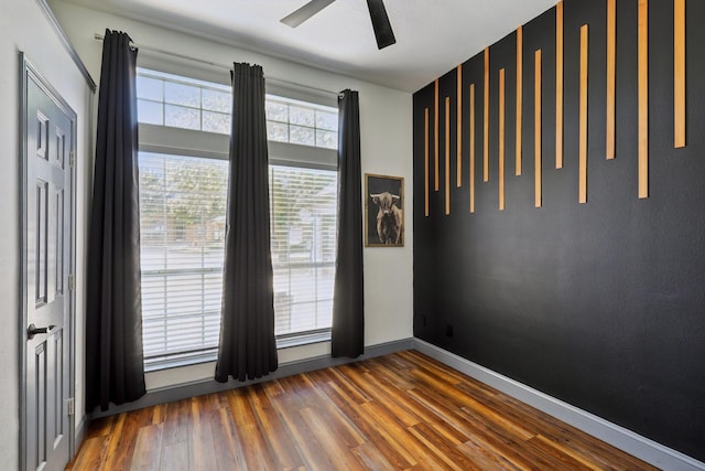 empty room featuring ceiling fan, wood finished floors, and baseboards