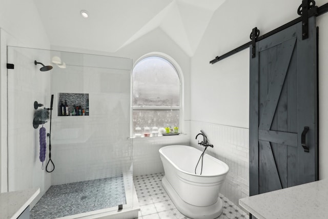 full bathroom with a tile shower, a soaking tub, vaulted ceiling, tile walls, and wainscoting