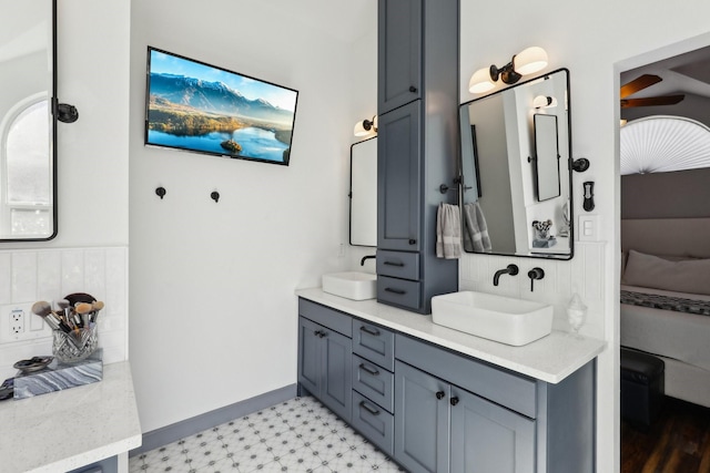 ensuite bathroom with tile patterned floors, double vanity, backsplash, ensuite bathroom, and a sink