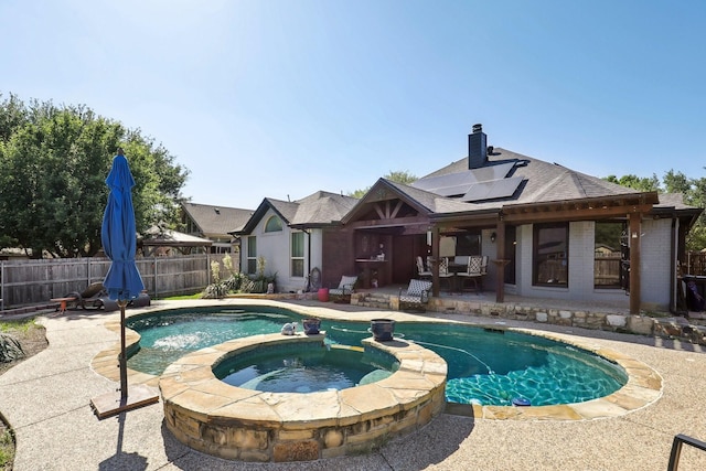 view of pool with a fenced backyard, a pool with connected hot tub, and a patio