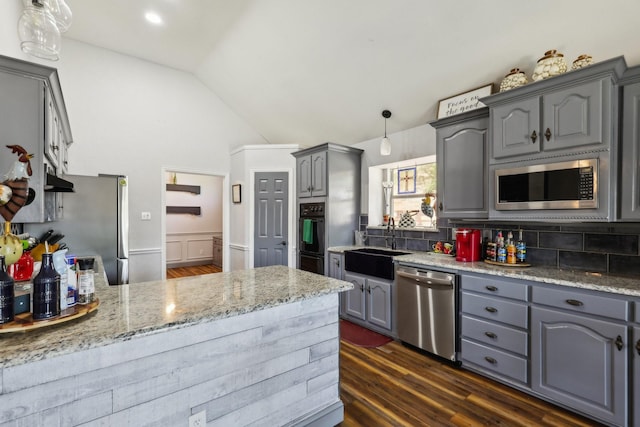 kitchen with a sink, decorative backsplash, gray cabinetry, appliances with stainless steel finishes, and lofted ceiling