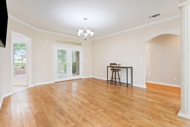 unfurnished room with light wood-type flooring, french doors, arched walkways, and a healthy amount of sunlight