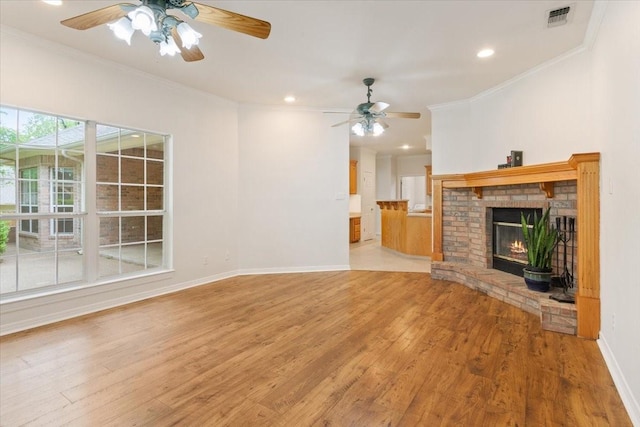 unfurnished living room featuring a ceiling fan, ornamental molding, visible vents, and light wood-type flooring