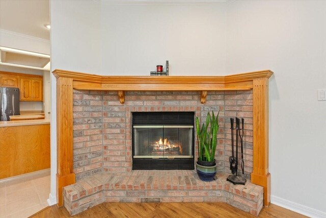room details with a fireplace, freestanding refrigerator, crown molding, and baseboards