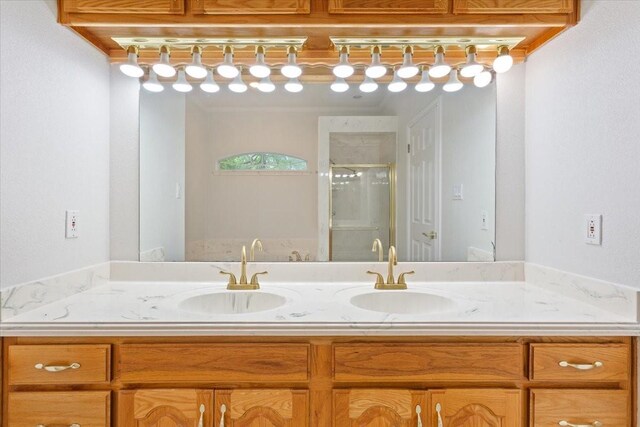 full bath with double vanity, a shower stall, and a sink