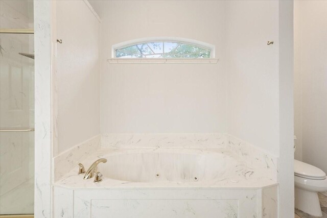full bath featuring toilet, a tub with jets, and a marble finish shower