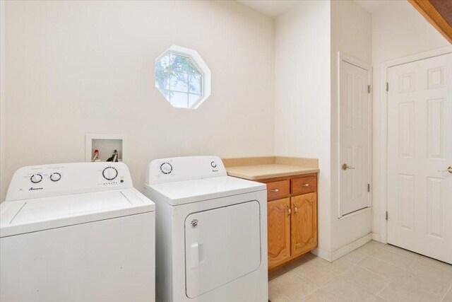 laundry area featuring washing machine and clothes dryer, cabinet space, and light tile patterned flooring