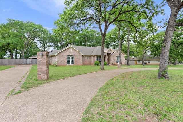 ranch-style home featuring fence, a front yard, aphalt driveway, and brick siding