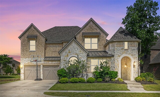 view of front facade featuring an attached garage, driveway, stone siding, and a standing seam roof