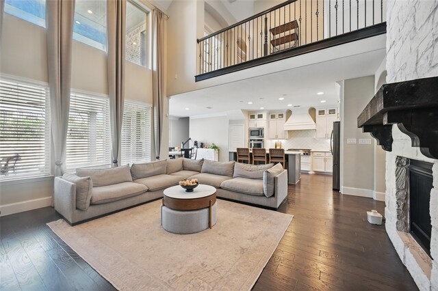 living room with a towering ceiling, dark wood-style flooring, baseboards, and a fireplace