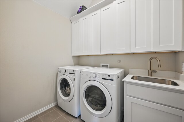 clothes washing area with cabinet space, a sink, baseboards, light tile patterned floors, and washer and clothes dryer
