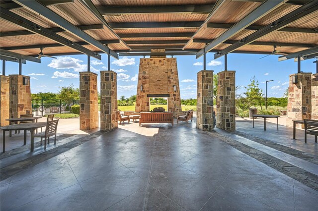 view of patio / terrace featuring a multi sided fireplace, a ceiling fan, and fence