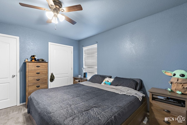 carpeted bedroom featuring ceiling fan and a textured wall