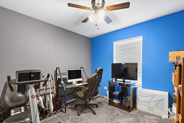 carpeted office with a textured wall, baseboards, and ceiling fan