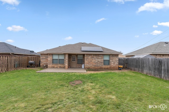 back of property featuring brick siding, solar panels, a fenced backyard, and a patio