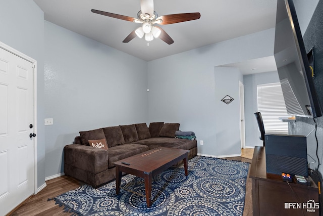 living area with baseboards, a ceiling fan, and wood finished floors