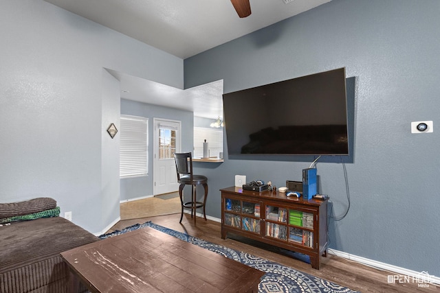 living room with ceiling fan, baseboards, and wood finished floors