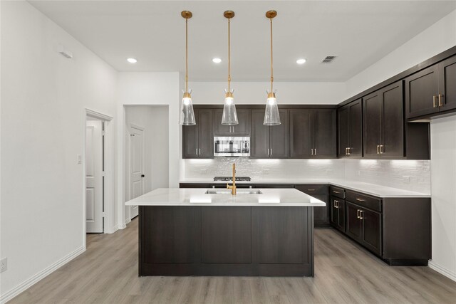 917 Janwood Dr, Plano, TX 75075 - kitchen featuring stainless steel microwave, light wood-type flooring, a sink, tasteful backsplash, and dark brown cabinets