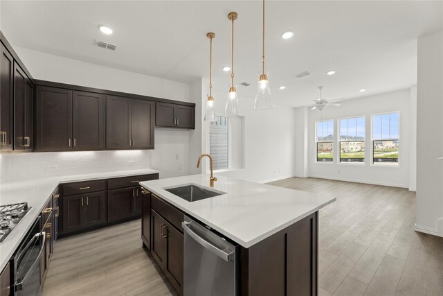 917 Janwood Dr, Plano, TX 75075 - kitchen featuring a sink, stainless steel appliances, dark brown cabinets, light wood-style flooring, and decorative backsplash