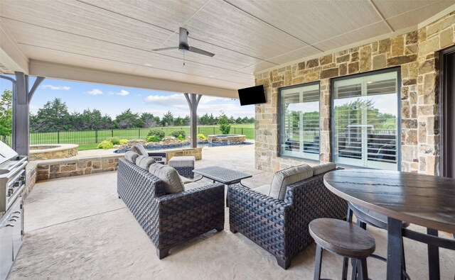 view of patio featuring a fenced backyard, a fire pit, ceiling fan, a pool with connected hot tub, and outdoor dining area