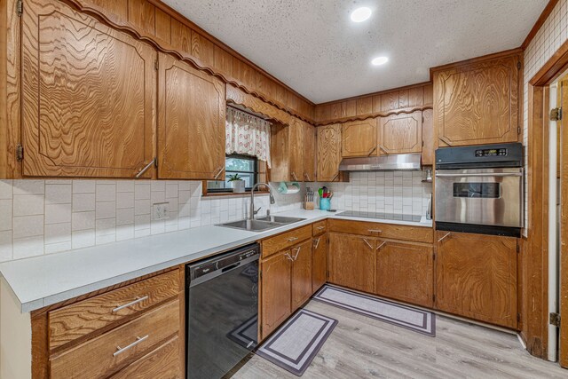 kitchen with under cabinet range hood, a sink, light wood-style floors, black appliances, and tasteful backsplash