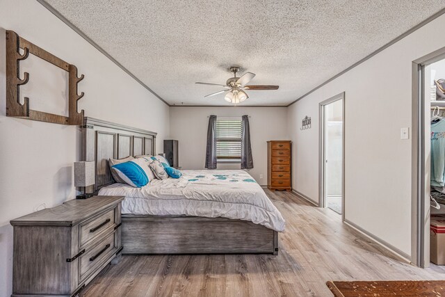 bedroom with light wood finished floors, ceiling fan, a textured ceiling, and ornamental molding