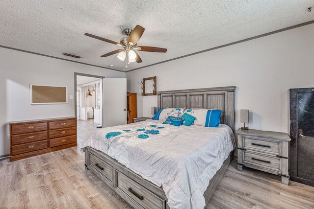bedroom featuring a ceiling fan, visible vents, a textured ceiling, and light wood finished floors