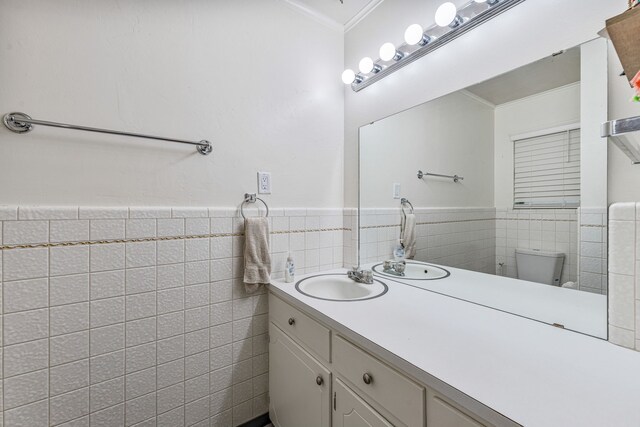 bathroom featuring wainscoting, toilet, ornamental molding, and tile walls
