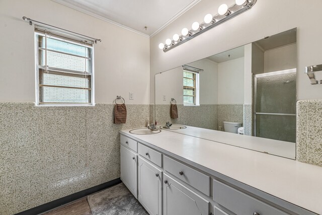 full bath featuring toilet, vanity, ornamental molding, tile walls, and wainscoting