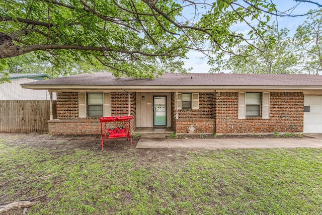single story home with fence, brick siding, a garage, a shingled roof, and a front yard
