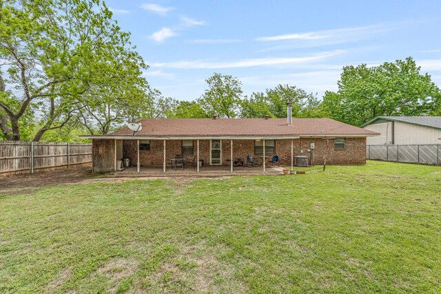 back of house featuring a lawn, a fenced backyard, brick siding, and a patio area
