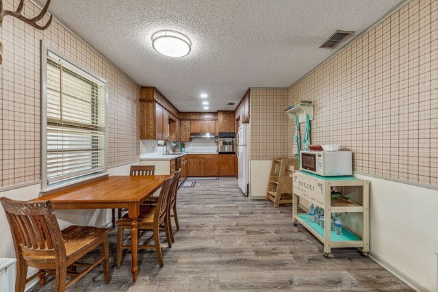 dining area featuring wood finished floors, a textured ceiling, and visible vents