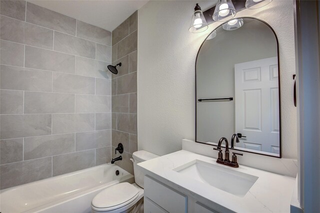 full bath with toilet, a textured wall, vanity, and shower / bathing tub combination