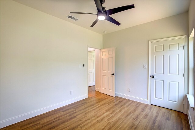 unfurnished bedroom with ceiling fan, baseboards, wood finished floors, and visible vents