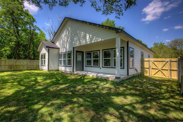 back of property featuring a lawn, a fenced backyard, and a gate