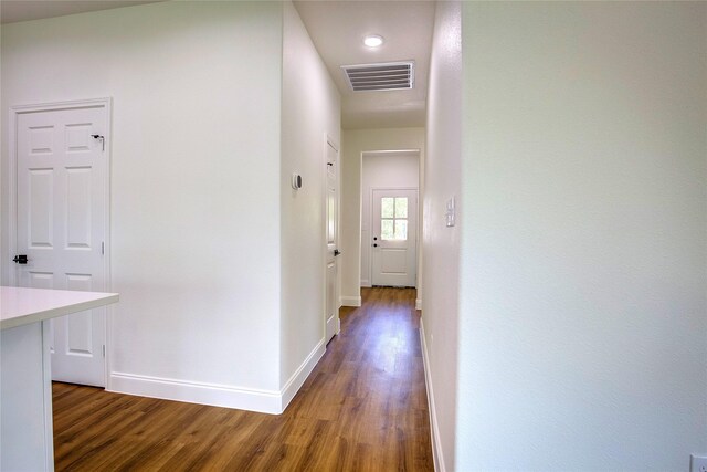 corridor featuring baseboards, wood finished floors, and visible vents