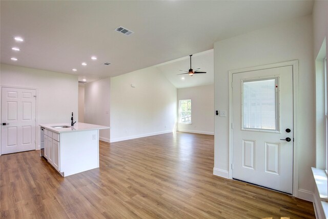 kitchen featuring a sink, light wood-type flooring, visible vents, white cabinetry, and a ceiling fan