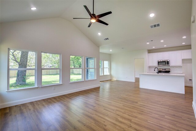 unfurnished living room with recessed lighting, visible vents, high vaulted ceiling, and a sink