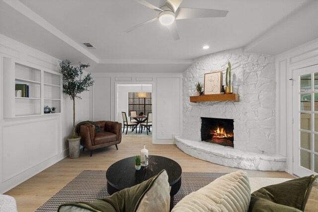 living area featuring light wood-style flooring, a fireplace, visible vents, a ceiling fan, and lofted ceiling