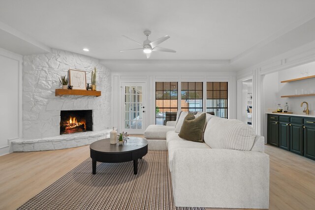 living area with recessed lighting, indoor wet bar, a stone fireplace, light wood finished floors, and a ceiling fan