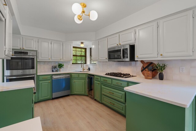 kitchen featuring light wood finished floors, a sink, stainless steel appliances, tasteful backsplash, and white cabinetry